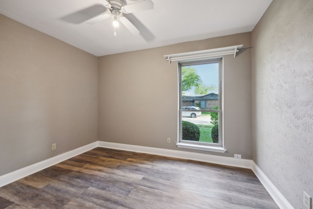 unfurnished room featuring a ceiling fan, a textured wall, baseboards, and dark wood finished floors