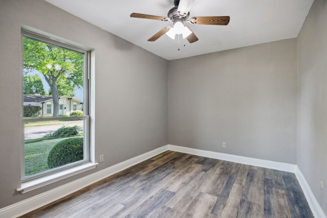 spare room with baseboards, a ceiling fan, and dark wood finished floors