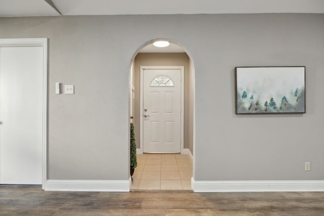entrance foyer with baseboards, arched walkways, and wood finished floors