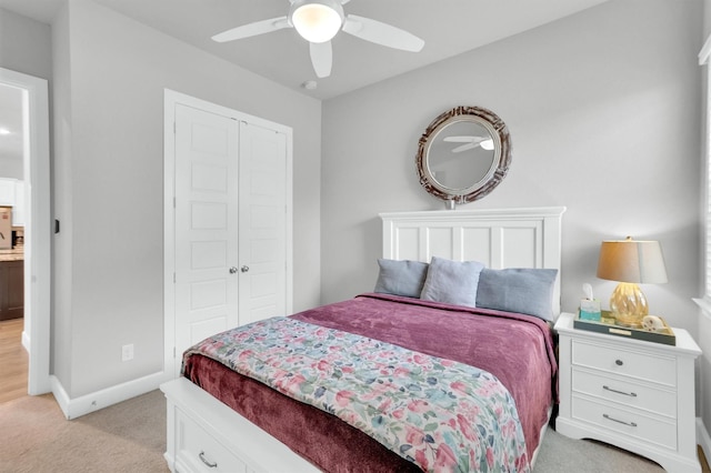 bedroom with light colored carpet, a closet, a ceiling fan, and baseboards
