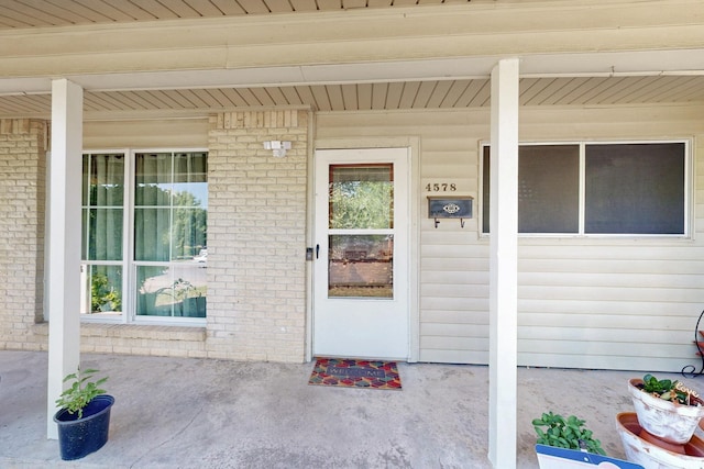 property entrance with brick siding and covered porch