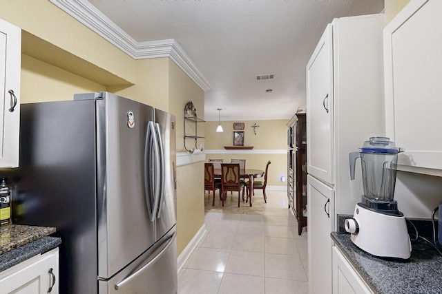 kitchen with white cabinets, visible vents, light tile patterned flooring, freestanding refrigerator, and baseboards