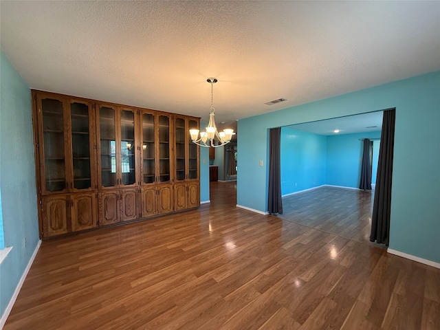 100 Russell St, Lorena, TX 76655 - unfurnished dining area featuring a chandelier, wood finished floors, baseboards, and a textured ceiling