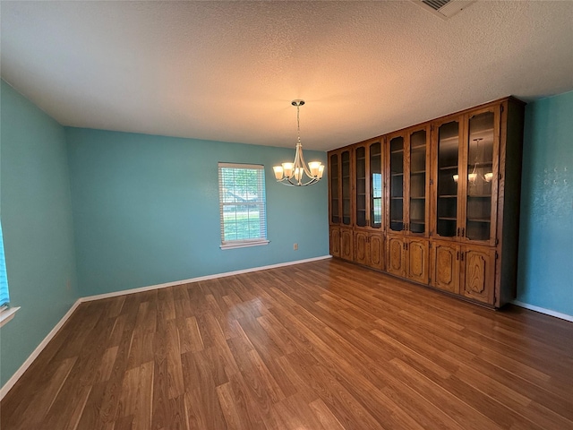 100 Russell St, Lorena, TX 76655 - unfurnished dining area featuring a chandelier, wood finished floors, baseboards, and a textured ceiling