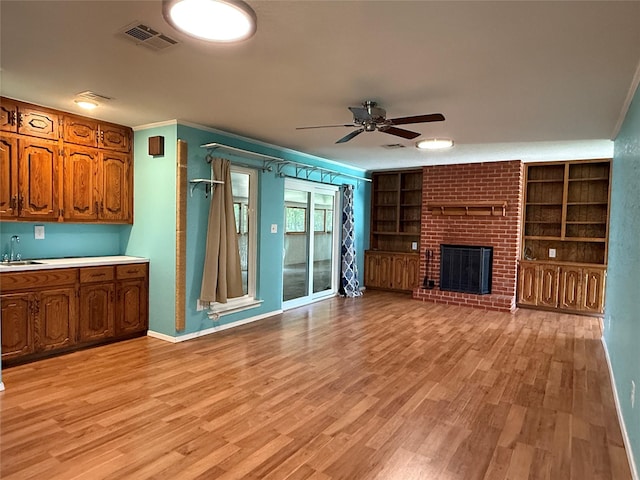 100 Russell St, Lorena, TX 76655 - unfurnished living room with a sink, ceiling fan, light wood finished floors, and a fireplace