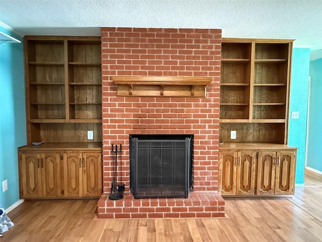 100 Russell St, Lorena, TX 76655 - unfurnished living room with light wood-style floors, a fireplace, a textured ceiling, and baseboards