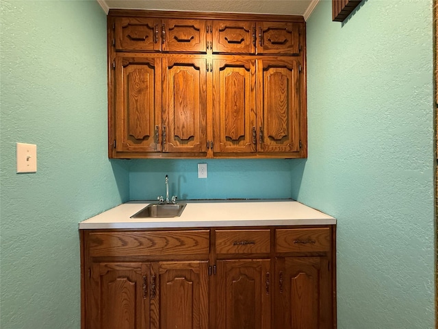 100 Russell St, Lorena, TX 76655 - kitchen featuring a sink, light countertops, brown cabinetry, and a textured wall
