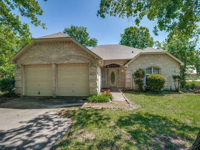 single story home with a front yard, brick siding, driveway, and a garage