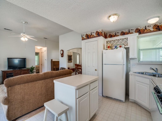 kitchen with a sink, freestanding refrigerator, visible vents, light countertops, and range