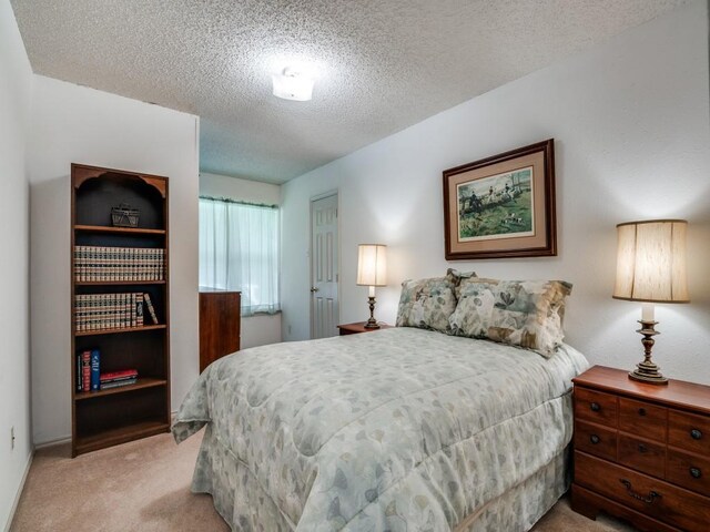 bedroom featuring light colored carpet and a textured ceiling