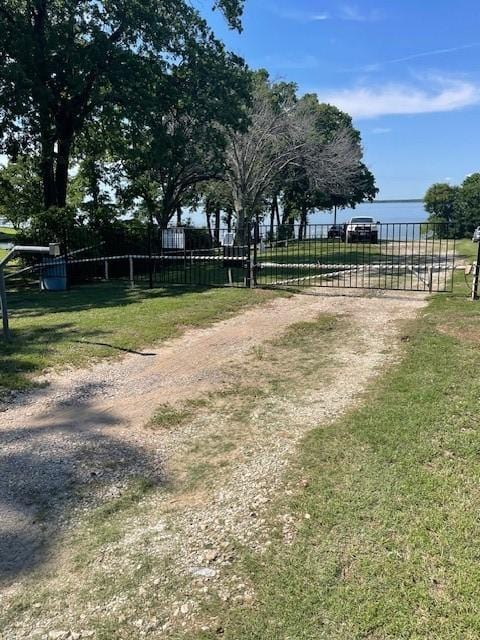 view of yard featuring a gate, fence, and dirt driveway
