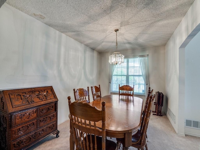 dining space featuring a textured ceiling, a notable chandelier, visible vents, and light colored carpet