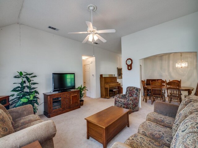 living room with light carpet, ceiling fan with notable chandelier, visible vents, and vaulted ceiling