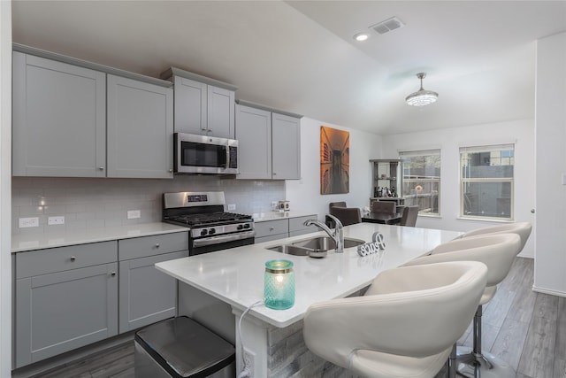 4512 Hiddenite Rd, Little Elm, TX 76227 - kitchen featuring appliances with stainless steel finishes, a sink, gray cabinetry, lofted ceiling, and backsplash