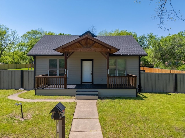 bungalow with a porch, a front lawn, a shingled roof, and fence
