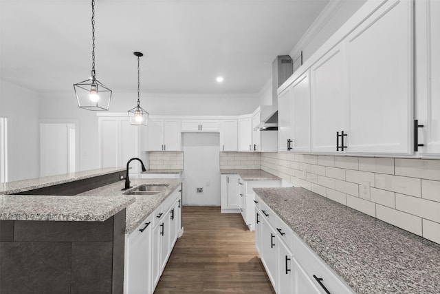 kitchen featuring crown molding, light stone counters, dark wood-style flooring, a sink, and backsplash