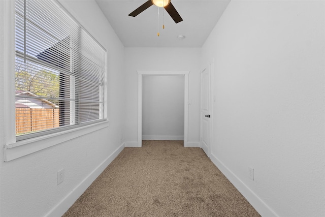 empty room with carpet, baseboards, and a ceiling fan