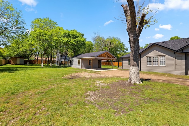 view of yard featuring a carport, driveway, and fence