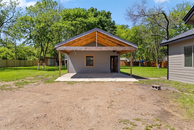 rear view of house with a yard, a patio, an outdoor structure, and fence