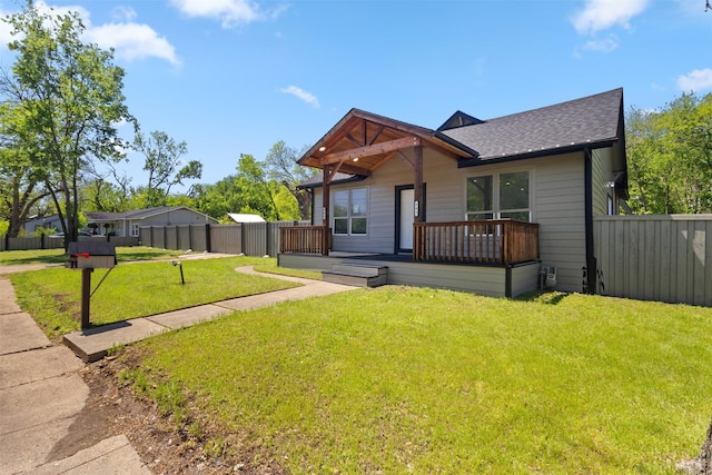 view of front of home featuring a shingled roof, a wooden deck, a front yard, and fence