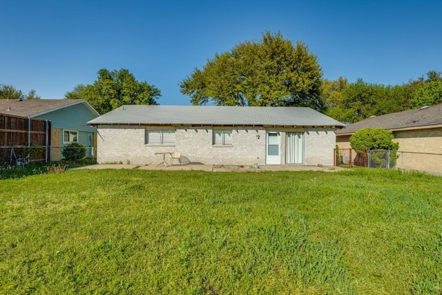 back of property featuring a yard, fence, and brick siding