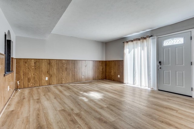 foyer entrance with wooden walls, a wainscoted wall, and wood finished floors