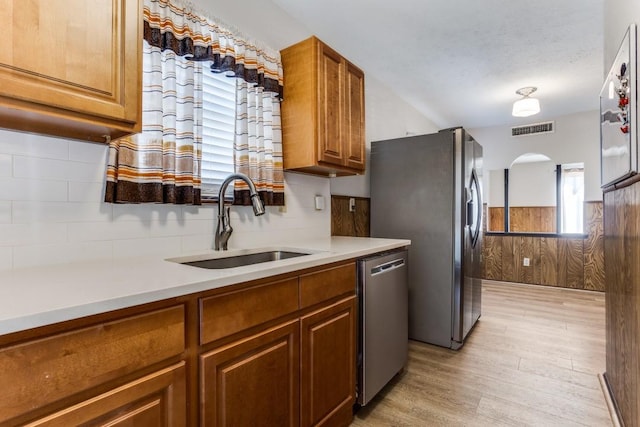 kitchen featuring visible vents, a sink, brown cabinets, stainless steel appliances, and light wood-style flooring