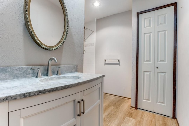 full bath featuring a closet, a shower, vanity, and wood finished floors