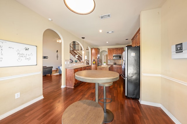 5038 W Fall Dr, Midlothian, TX 76065 - kitchen featuring dark wood-type flooring, arched walkways, appliances with stainless steel finishes, light countertops, and brown cabinets