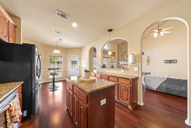 5038 W Fall Dr, Midlothian, TX 76065 - kitchen featuring arched walkways, visible vents, freestanding refrigerator, and dark wood-style floors