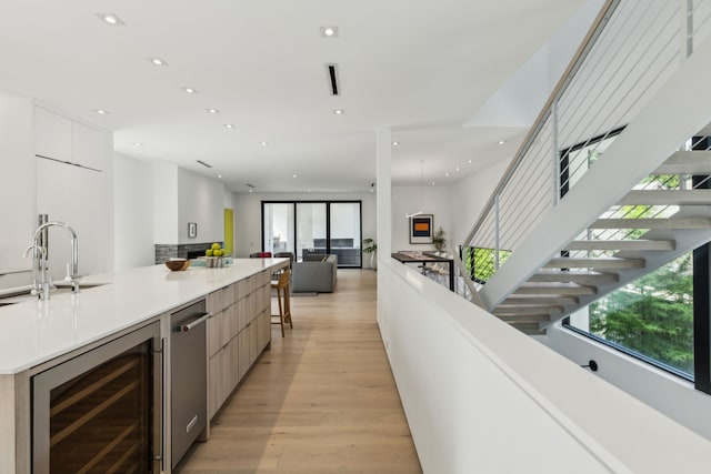 5101 Vickery Blvd, Dallas, TX 75206 - kitchen with modern cabinets, beverage cooler, light wood finished floors, a sink, and recessed lighting