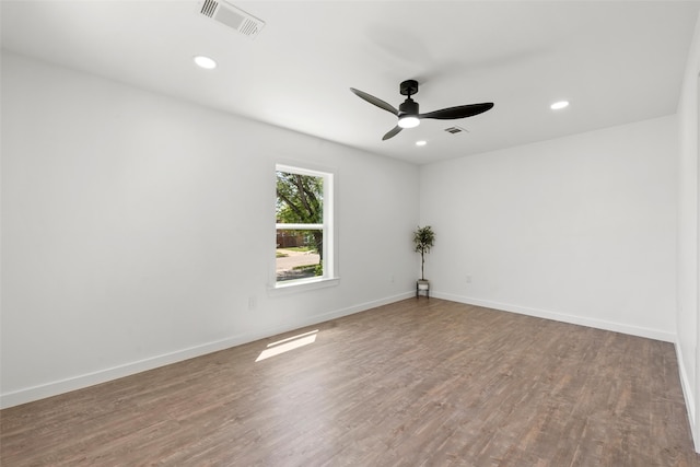 spare room with wood finished floors, visible vents, and ceiling fan