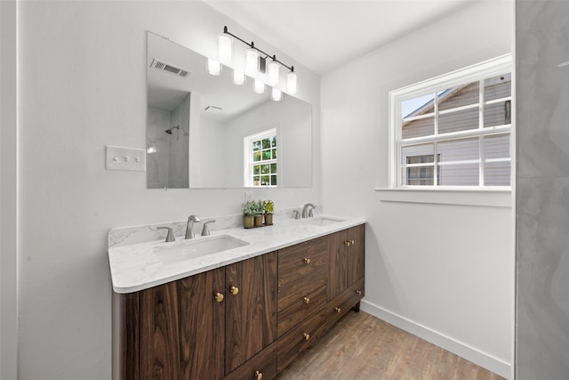 full bathroom with baseboards, wood finished floors, visible vents, and a sink