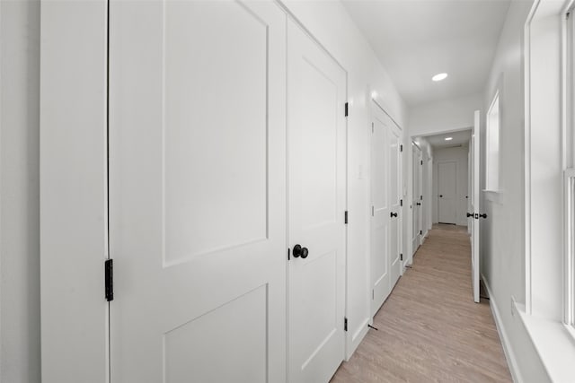 hallway featuring light wood-style flooring, baseboards, and recessed lighting