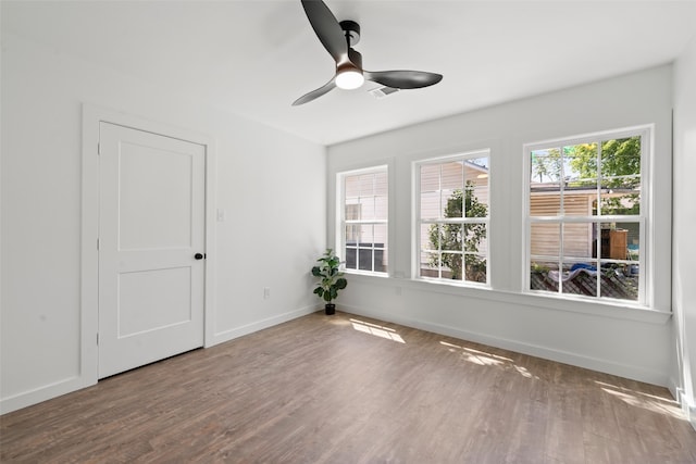 empty room featuring baseboards, a ceiling fan, and wood finished floors