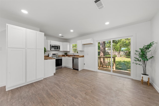 kitchen with a sink, light wood-style floors, white cabinets, appliances with stainless steel finishes, and visible vents