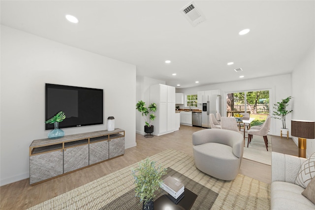 living area with baseboards, light wood-style flooring, visible vents, and recessed lighting