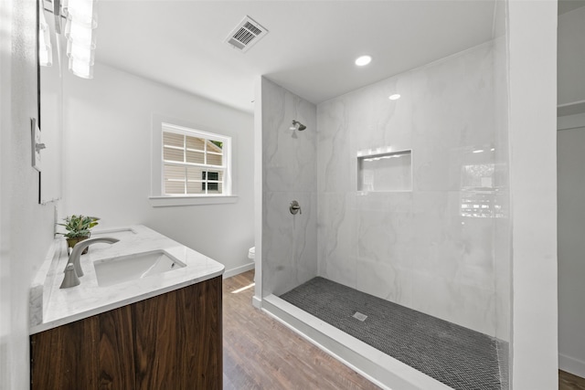full bath with a sink, toilet, visible vents, wood finished floors, and a walk in shower