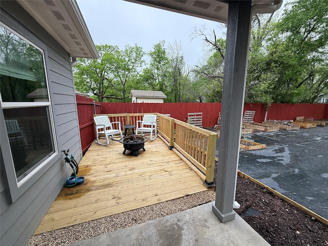 wooden deck featuring a fenced backyard and a fire pit