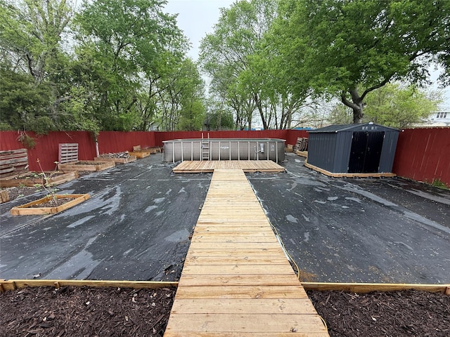 wooden deck with an outbuilding, a fenced backyard, and a shed