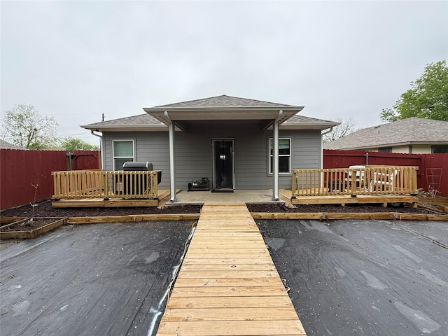 rear view of property with a fenced backyard, a shingled roof, and a deck