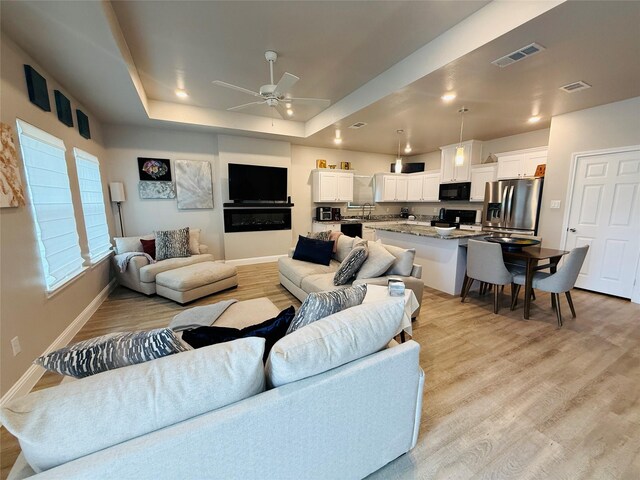 living area featuring light wood-style floors, visible vents, and ceiling fan