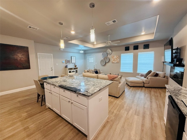 kitchen with a raised ceiling, dishwashing machine, visible vents, and light wood-style flooring