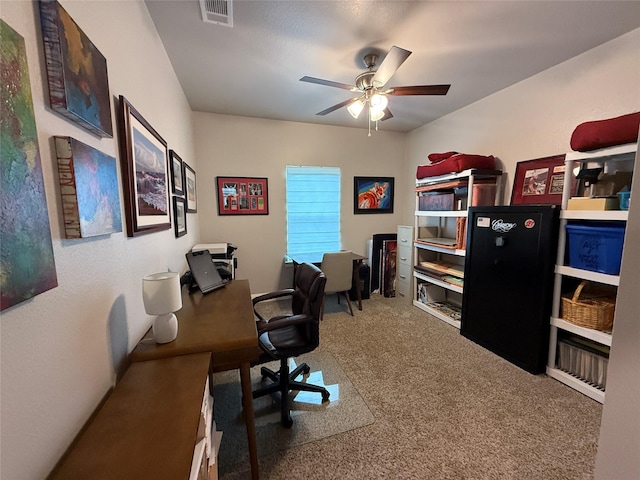 carpeted home office with ceiling fan and visible vents