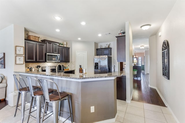 714 Lone Star Ct, Wylie, TX 75098 - kitchen featuring stainless steel appliances, light stone counters, decorative backsplash, a peninsula, and a breakfast bar area