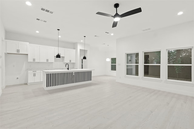 interior space featuring open floor plan, visible vents, light countertops, and light wood finished floors