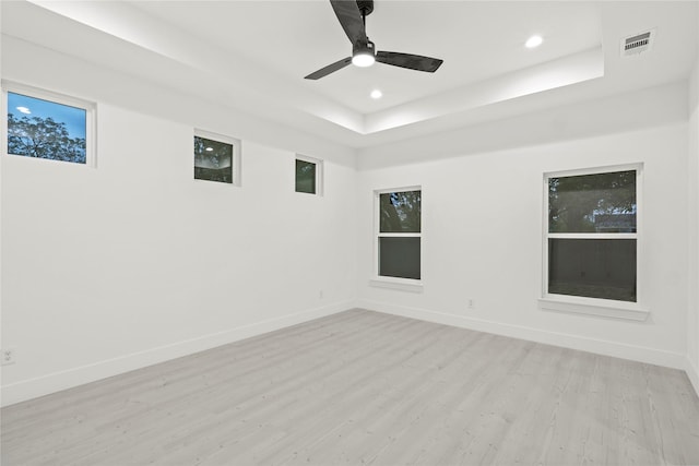 spare room featuring visible vents, baseboards, light wood-type flooring, a tray ceiling, and recessed lighting