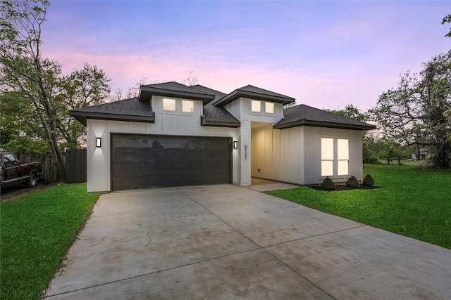 prairie-style house featuring a front yard, an attached garage, fence, concrete driveway, and roof with shingles