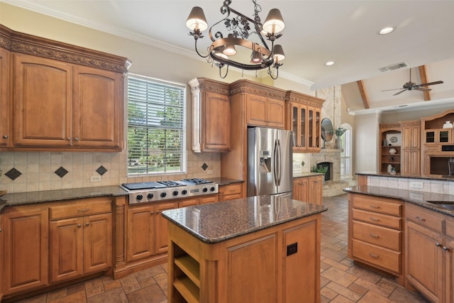 kitchen featuring stainless steel appliances, ceiling fan with notable chandelier, brown cabinetry, and a kitchen island