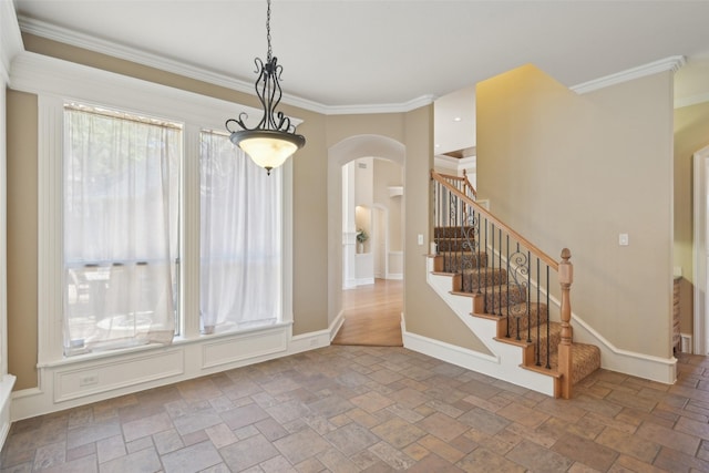 unfurnished dining area with crown molding, stairs, stone tile flooring, and arched walkways